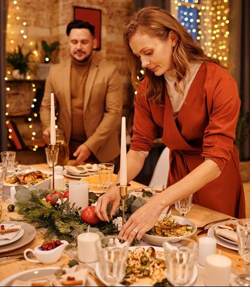 A couple setting the table for a holiday meal.