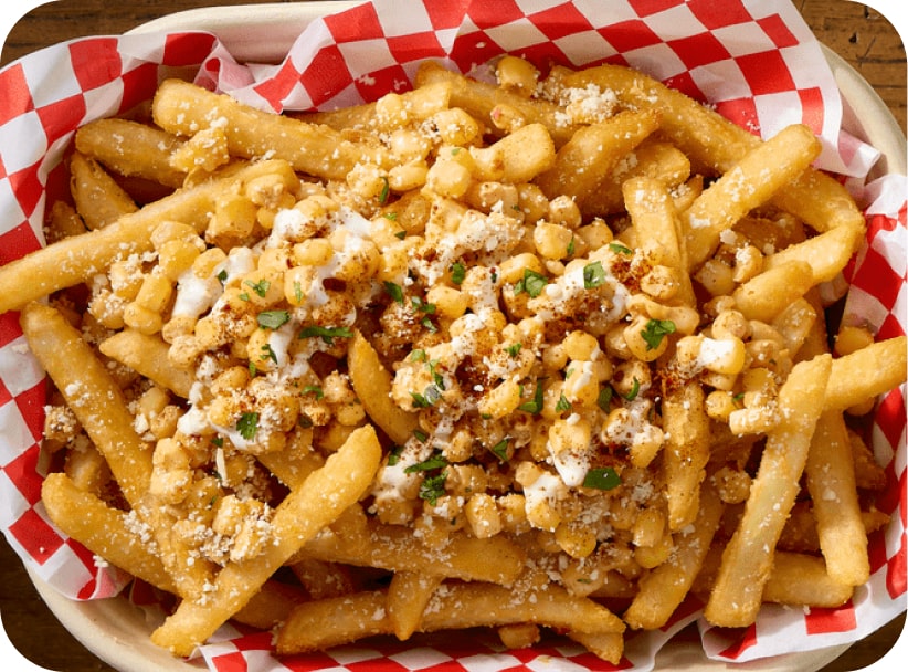 Basket of McCain® SureCrisp® fries topped with corn, cheese, and herbs.