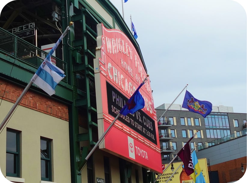 Angled view of the iconic Wrigley Field marquee with flags flying above the Chicago Cubs® entrance.
