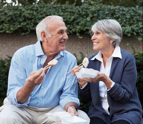 A couple enjoying food from a to-go container.