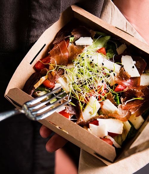 A salad in a takeout container.